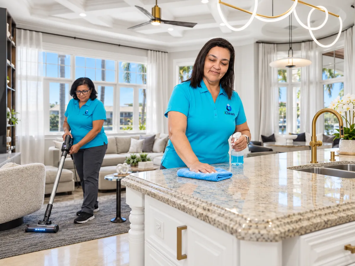 Iris and Carla from iClean cleaning a kitchen island and vacuuming a living room together