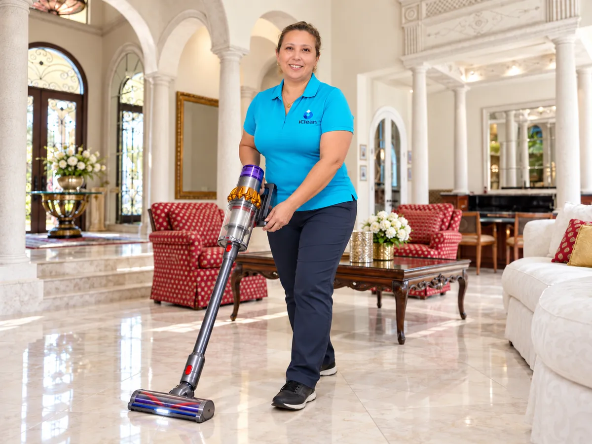 Rosani from iClean vacuuming a living room with red armchairs